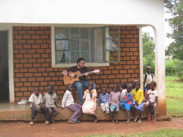 Lucas playing guitar with children at a school